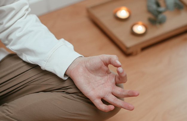 Hand resting near small candles for relaxation